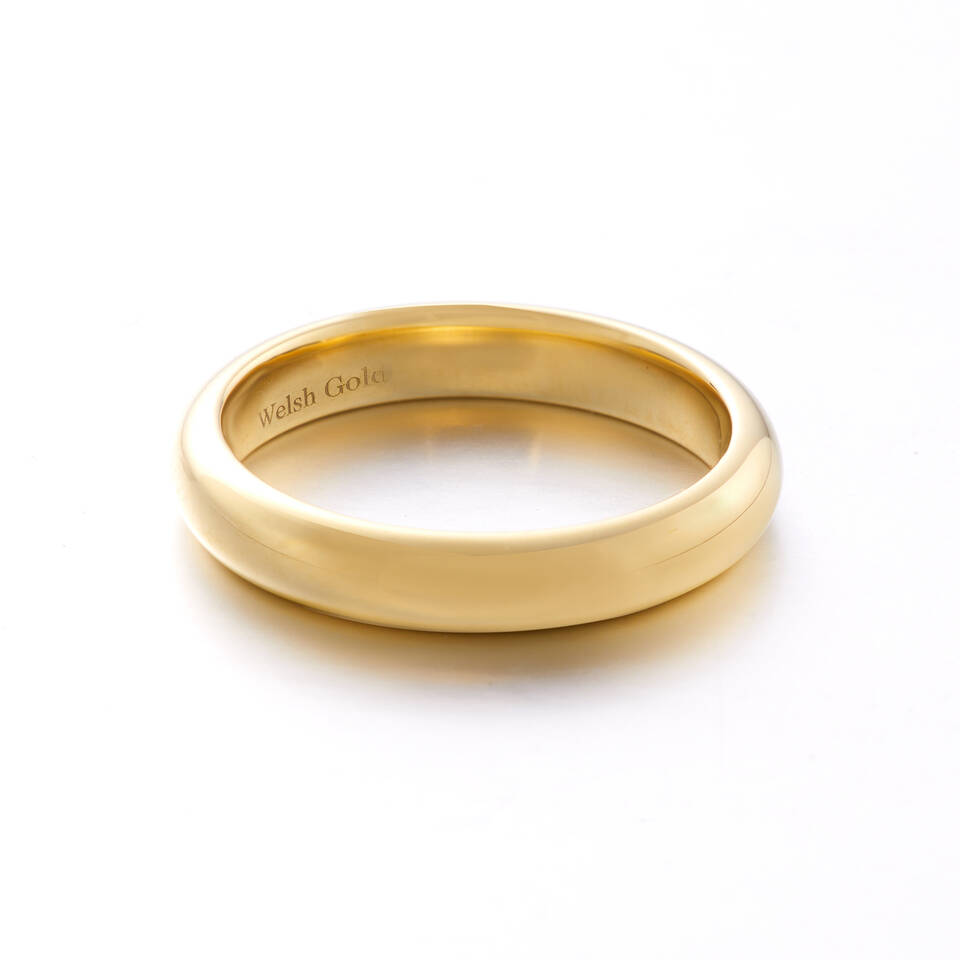 A high-polish gold wedding ring with a raised court profile, featuring a smooth, rounded exterior and a 'Welsh Gold' hallmark engraved on the inner surface.