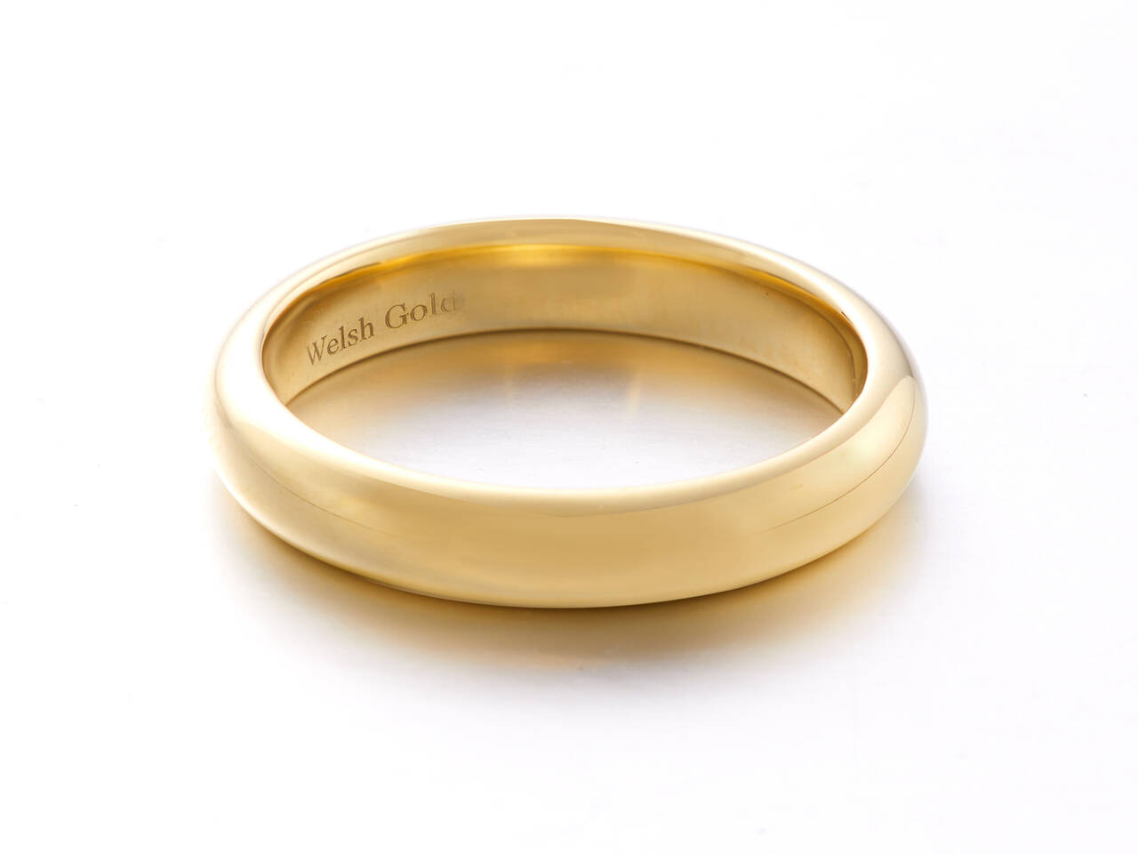 A high-polish gold wedding ring with a raised court profile, featuring a smooth, rounded exterior and a 'Welsh Gold' hallmark engraved on the inner surface.
