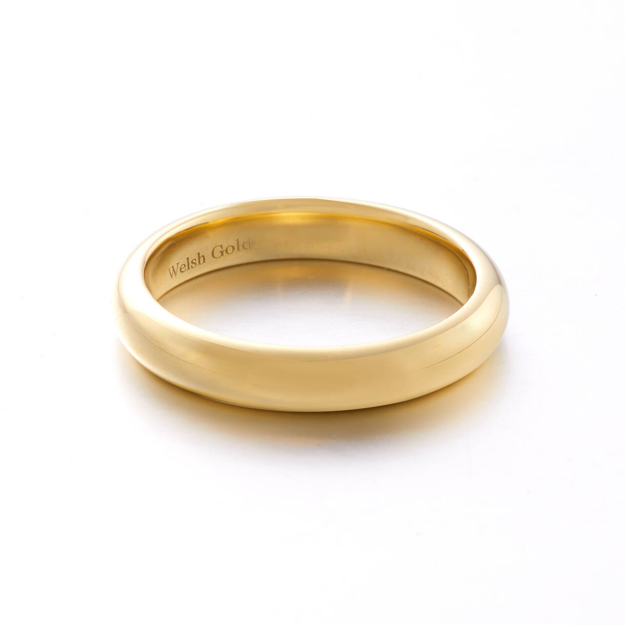A high-polish gold wedding ring with a raised court profile, featuring a smooth, rounded exterior and a 'Welsh Gold' hallmark engraved on the inner surface.