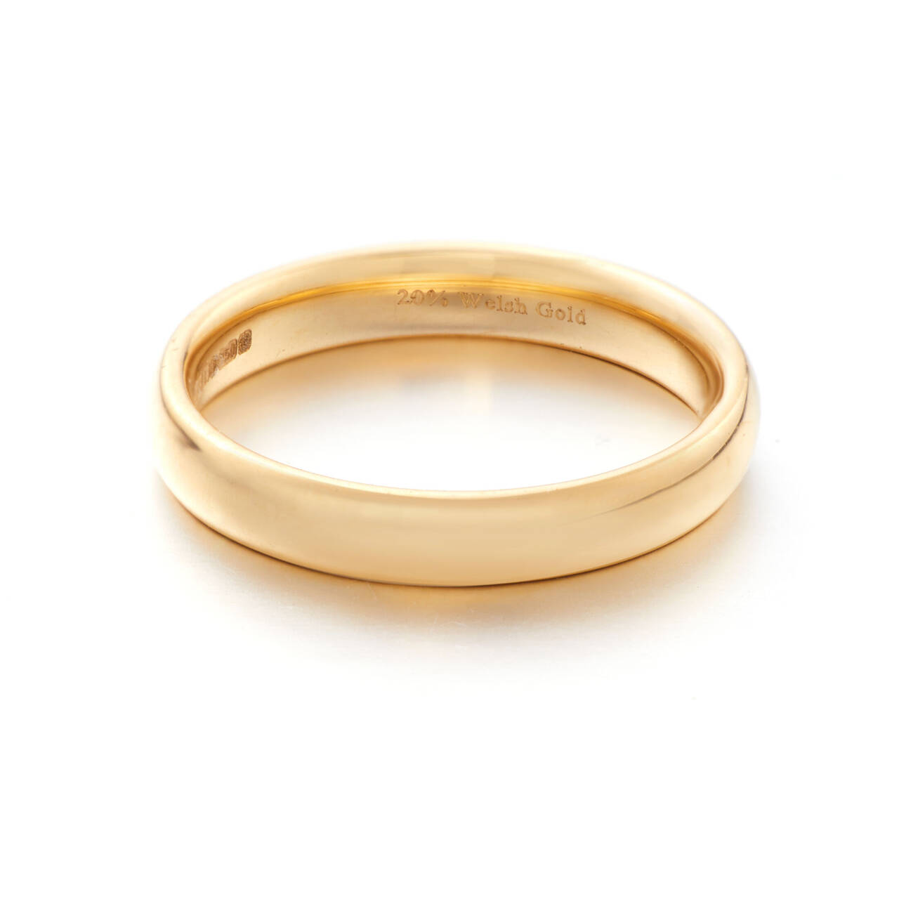 A close-up view of the inside of a polished gold wedding band, clearly showing the engraved hallmark '20% Welsh Gold' alongside official hallmarking stamps.