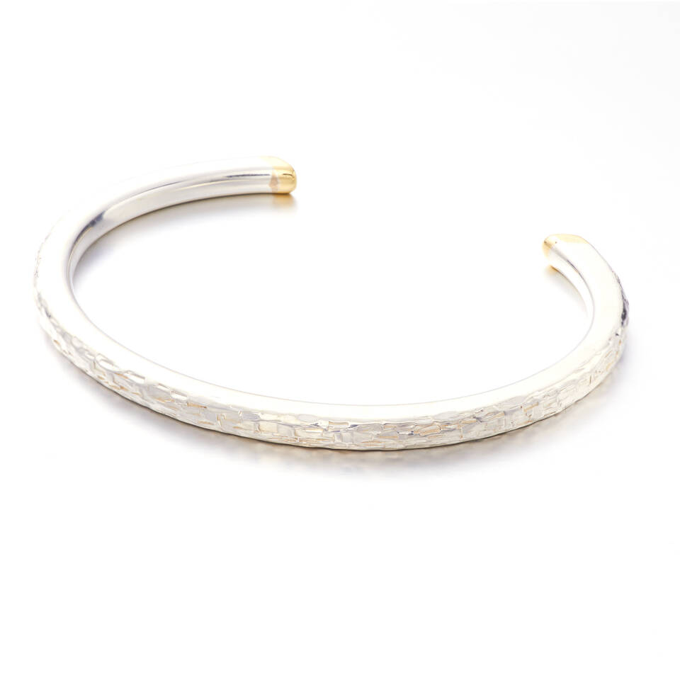 An elegant open-style torque bangle featuring a distinctively hammered sterling silver body finished with smooth, contrasting Welsh gold tips at each end.