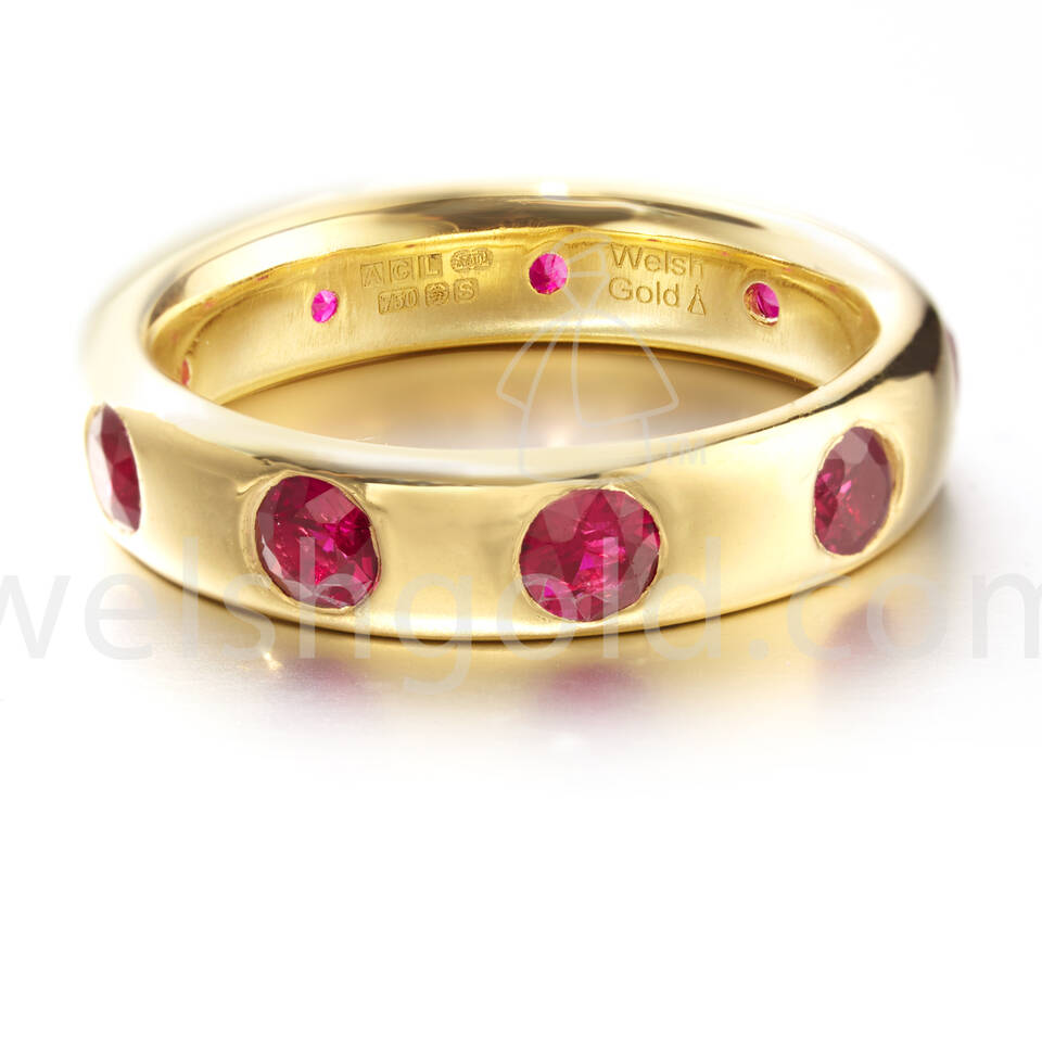 Elegant Welsh Gold ring set with vibrant pink rubies, displaying the authentic brand signature and gold purity stamps inside the band.