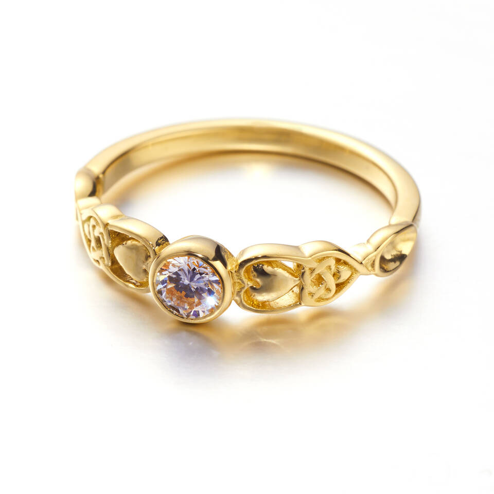 An 18ct Welsh gold Love Spoon ring featuring a central round bezel-set diamond flanked by intricate gold knotwork and heart details on a plain white background available in 20% or 100% Welsh gold