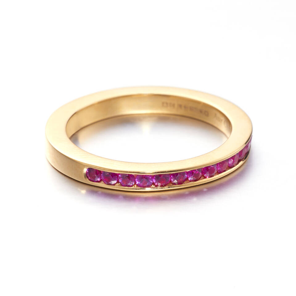 Elegant Welsh Gold handcrafted eternity ring showcasing precision channel-set rubies and a modern, flat-edged gold profile.