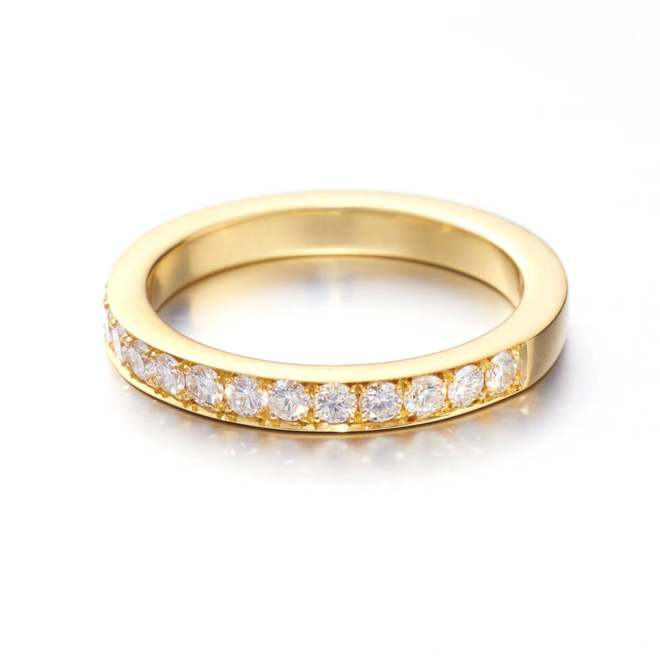 A polished yellow gold eternity band featuring a half-circle of brilliant-cut white diamonds pavé-set into the ring's surface.