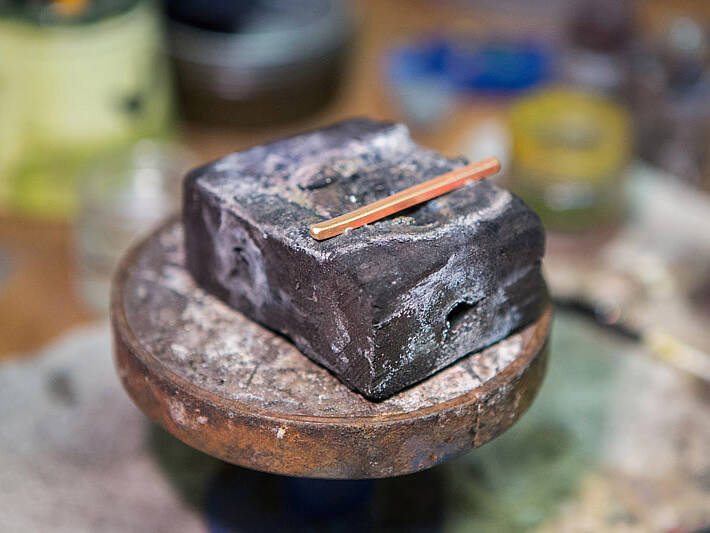 Handcrafting a Welsh gold ring: a precision-milled gold bar sits on a jeweller's soldering station prepared for the next stage of hand-bending and soldering.