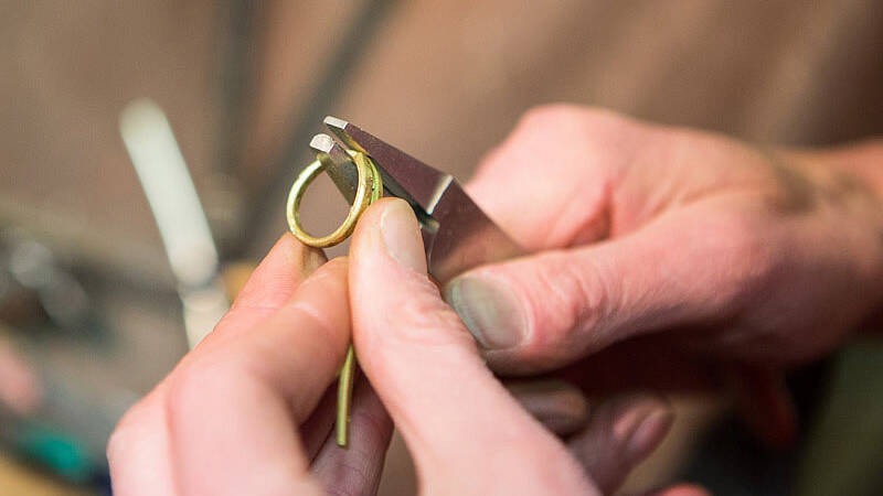 Handcrafting a Welsh gold wedding ring: an artisan uses specialised tools to form a 100% pure gold bar into a perfect circle.
