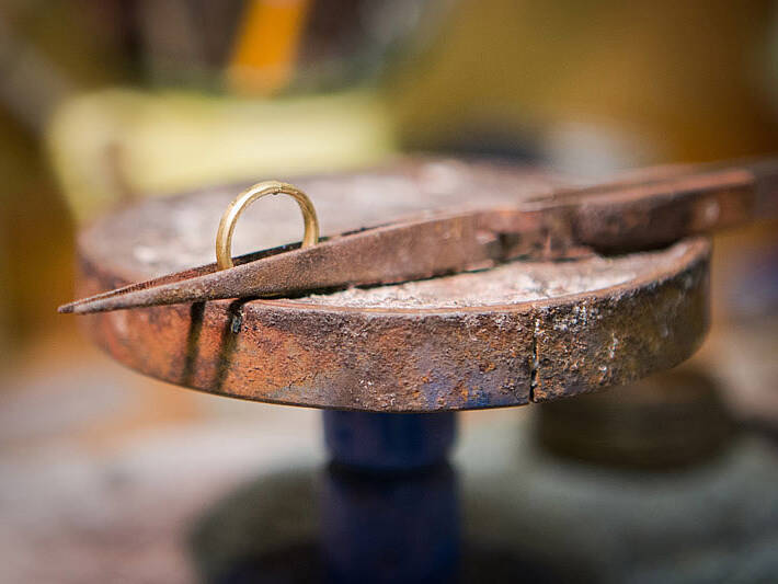 Handcrafting a Welsh gold ring: the band is held in place with specialised tweezers before the final soldering process joins the metal into a seamless circle.
