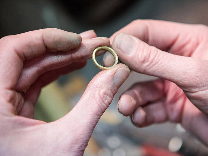 Handcrafting a Welsh gold wedding ring: the final stage of inspection where the handmade band is checked for precision and quality before final polishing.