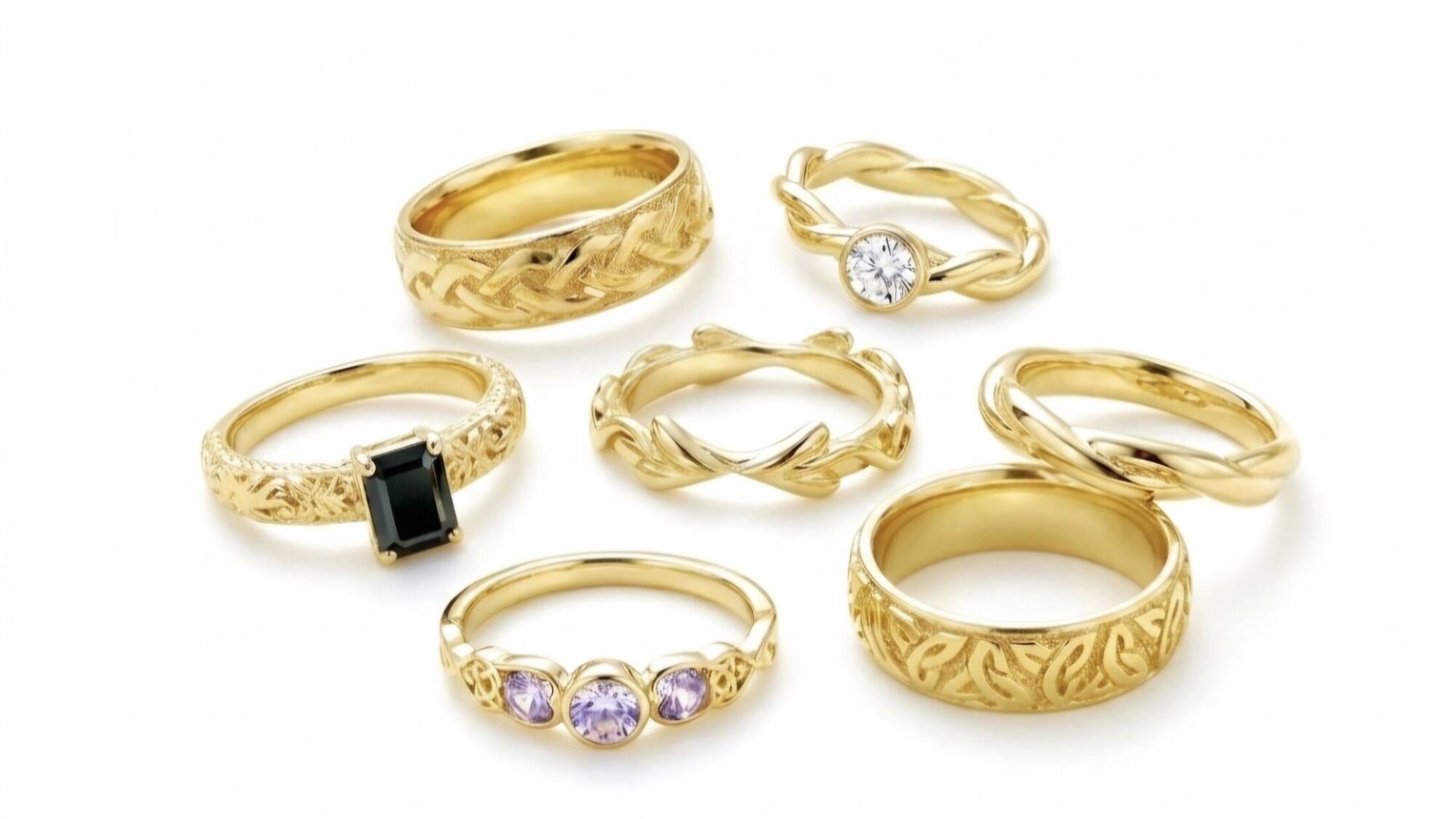 A arrangement of handcrafted Welsh gold Celtic rings featuring intricate knotwork wedding bands, gemstone engagement rings, and woven designs.