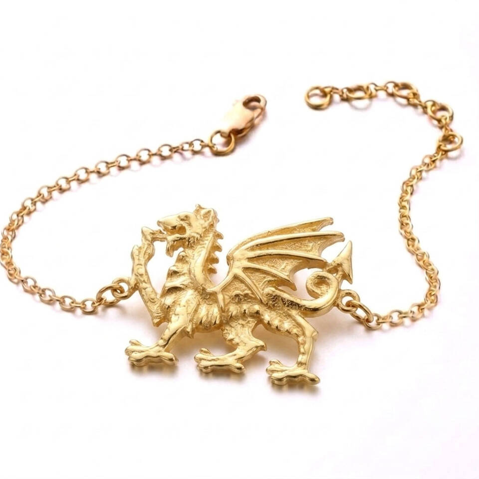 A finely detailed 18ct Welsh Gold bracelet featuring the iconic Welsh Dragon (Y Ddraig Goch) motif on a delicate trace chain with an adjustable link. The dragon pendant is central, and the solid gold piece is shown against a plain white background.