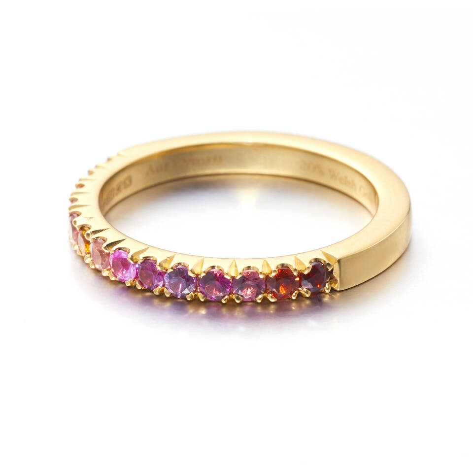 A vibrant Welsh gold ring featuring a half-circle of brilliant-cut colourful sapphires ranging from deep rose to pale gold.