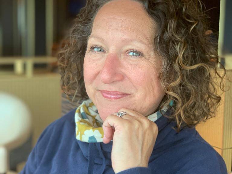 Headshot of Nikki, Goldsmith at Welsh Gold, smiling in a café setting.