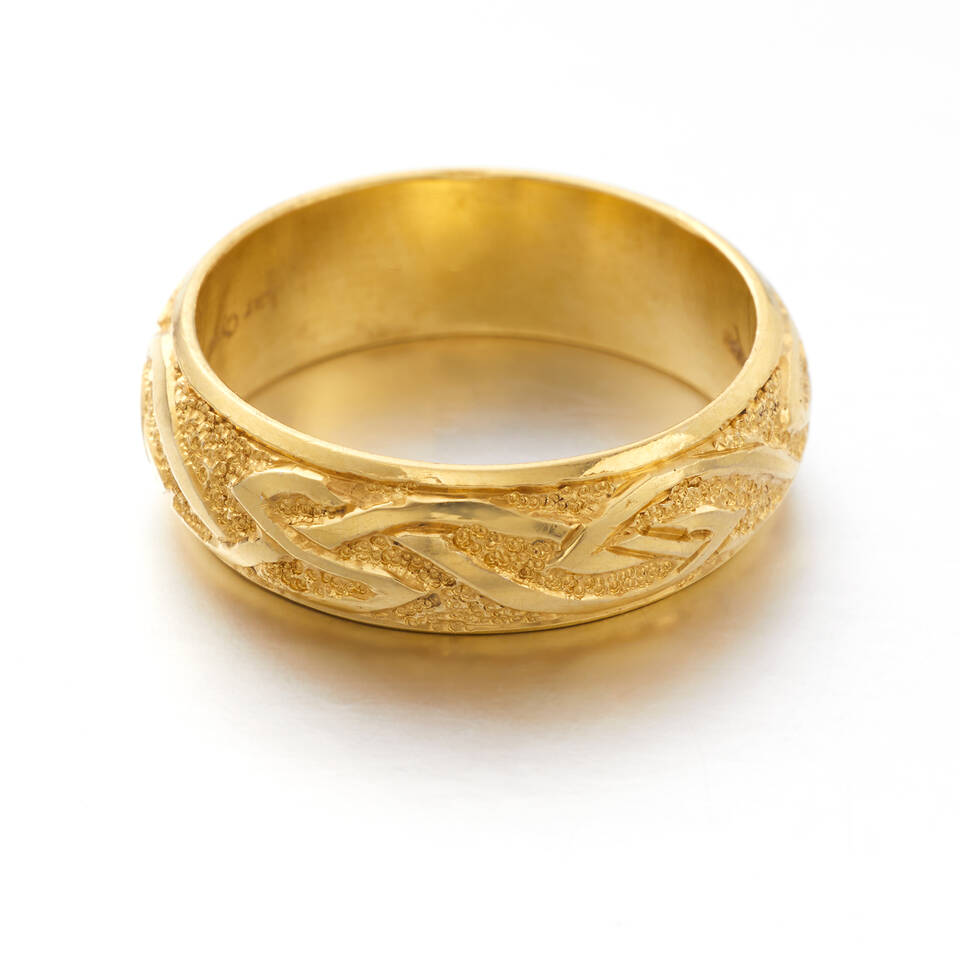A wide gold wedding band featuring a continuous raised Celtic knot pattern crafted in authentic Welsh gold.